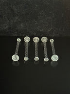 Close-up of a set of spiral glass cocktail muddlers on a black background