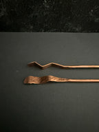 Two copper tongs on a dark gray background