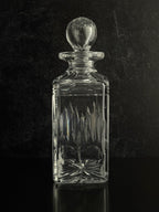 Clear glass decanter with a spherical stopper on a black background