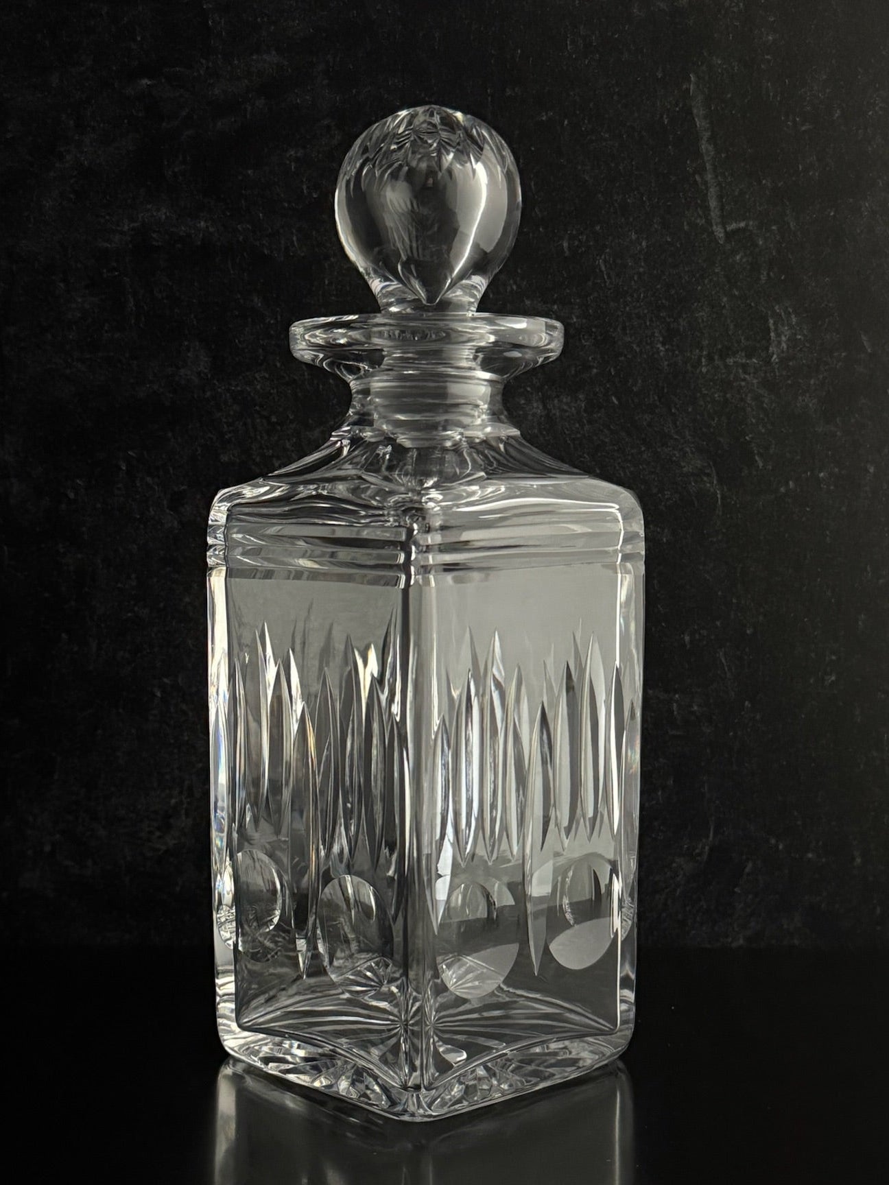 Clear glass decanter with a stopper on a black background