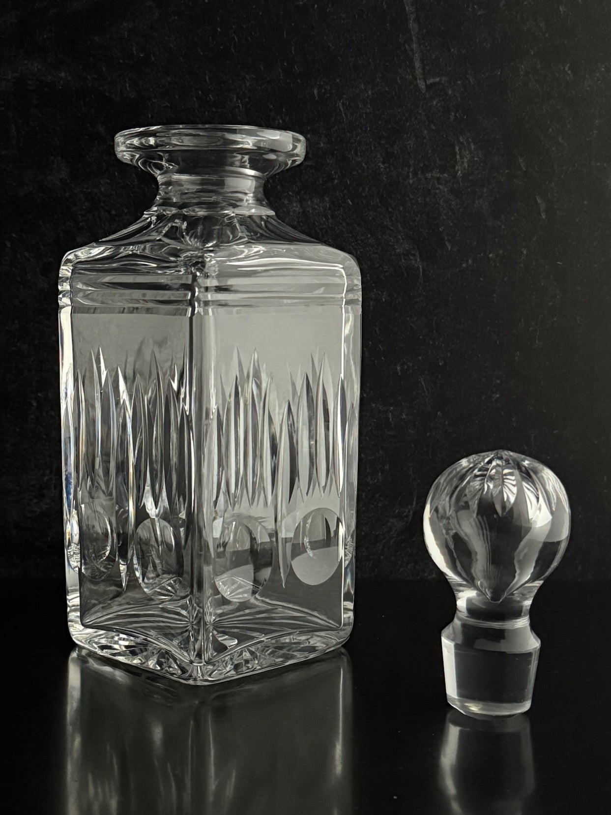 Clear glass decanter with stopper on a black background
