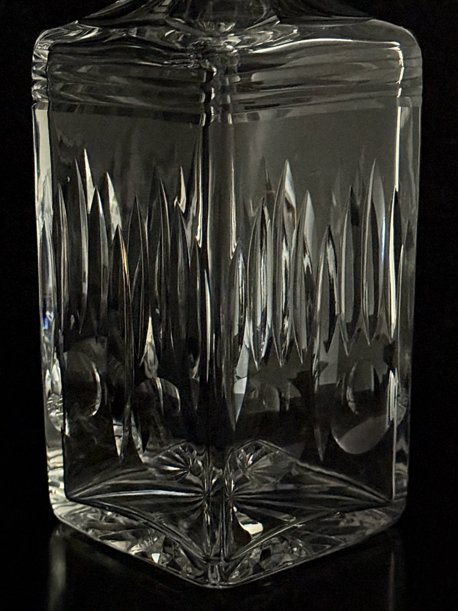 Clear glass decanter with intricate patterns on a black background