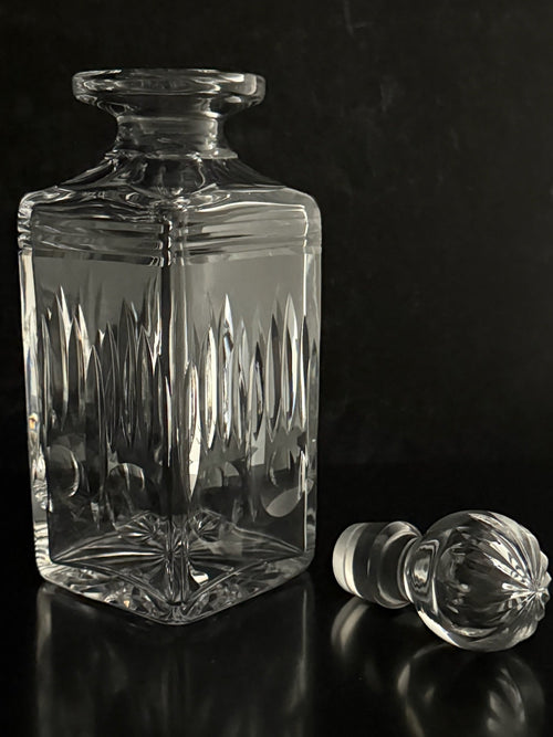 Clear glass decanter with stopper on a black background