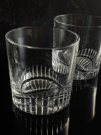 Two clear cut-crystal glasses with textured ribbed patterns, shown on a dark reflective surface.