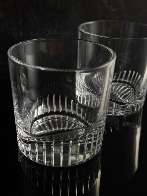 Two clear cut-crystal glasses with textured ribbed patterns, shown on a dark reflective surface.